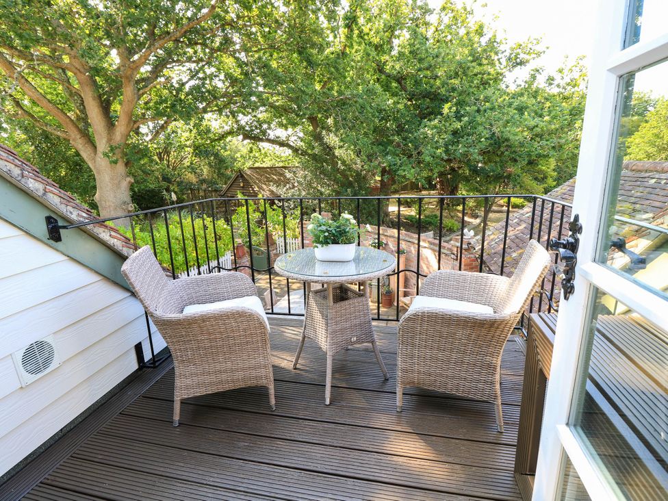 A balcony with a table and chairs overlooking greenery at Beam Cottage in Warsash