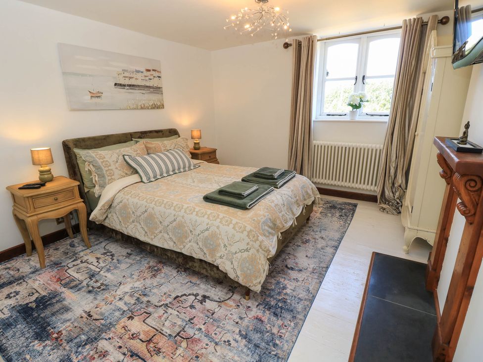 A bedroom with a bed and bedside table at Beam Cottage in Warsash