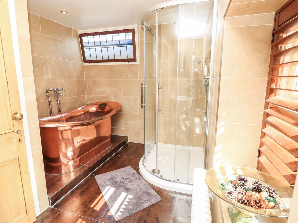 A bathroom with a copper bathtub and a glass shower at Beam Cottage in Warsash