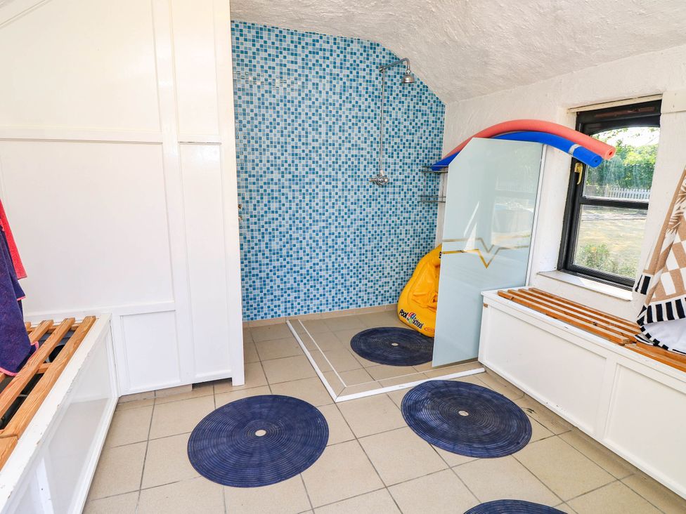 A bathroom with a shower and tiled wall at Beam Cottage in Warsash