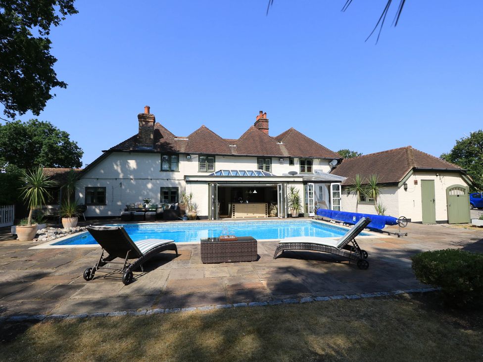 A house with a swimming pool and lounge chairs at Beam Cottage in Warsash