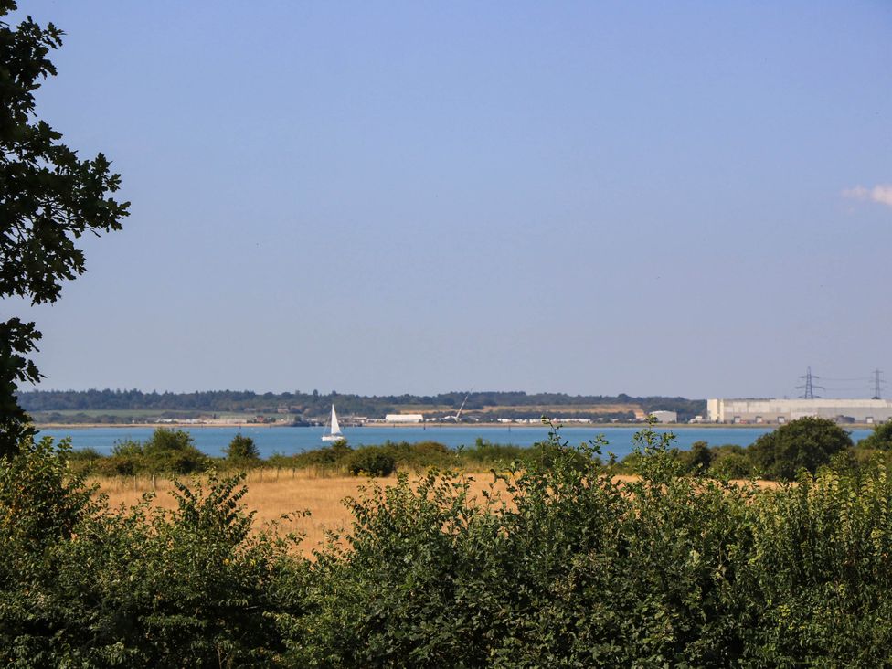 A view of water with a sailboat and buildings at Beam Cottage in Warsash