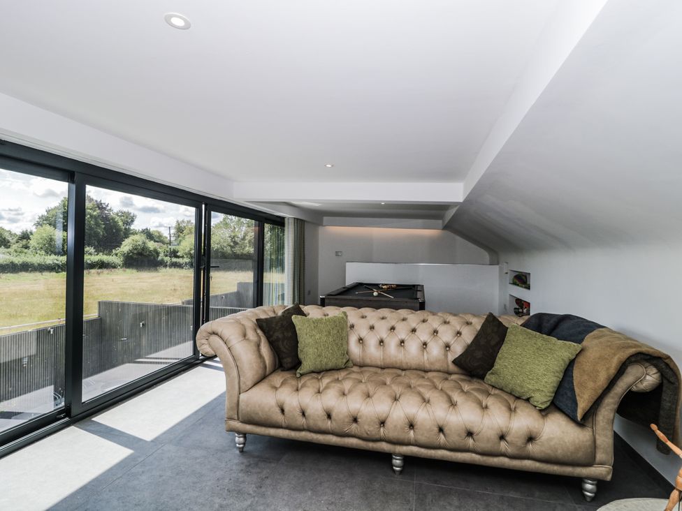 A living room with a sofa and large windows at Number 7 Bishop Sutton