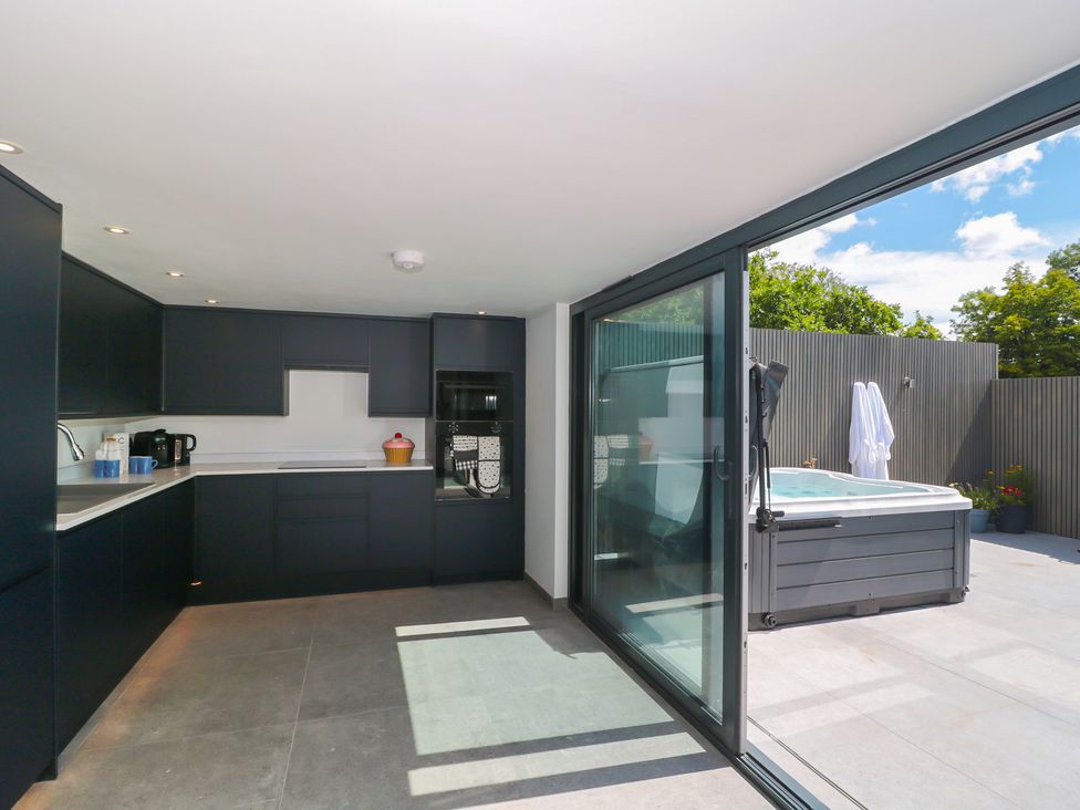 A kitchen with dark cabinets and a hot tub outside at Number 7 Bishop Sutton