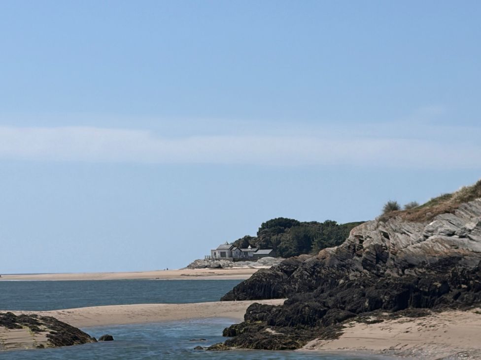 A beach with rocks and a house in the background at The Quarterdeck in Borth-Y-Gest