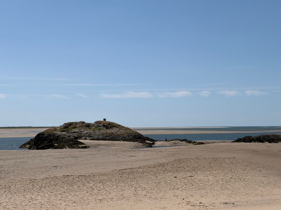 A beach with rocks and water at The Quarterdeck in Borth-Y-Gest