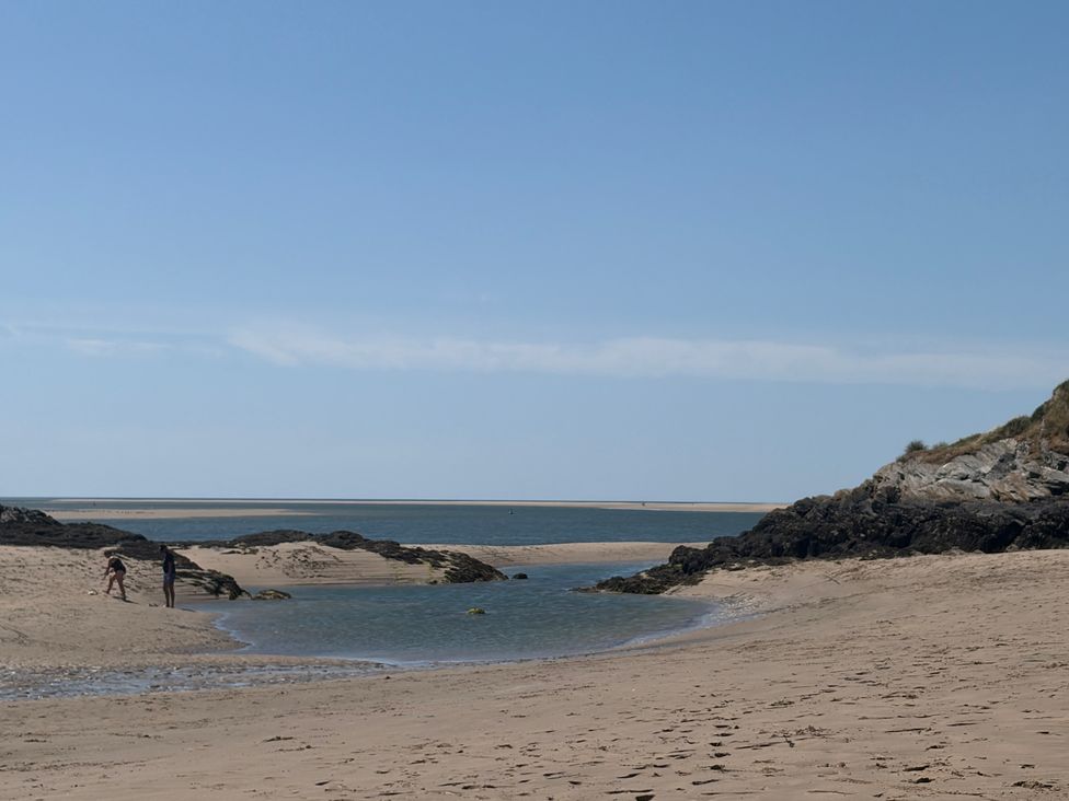 A beach with water and rocks at The Quarterdeck in Borth-Y-Gest