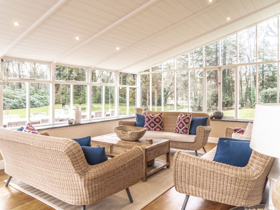A conservatory with wicker furniture and a coffee table at Tan Llan Llanelltyd near Dolgellau