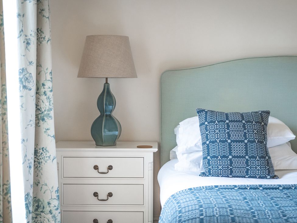 A bedroom with a bedside table and lamp at Tan Llan in Llanelltyd near Dolgellau