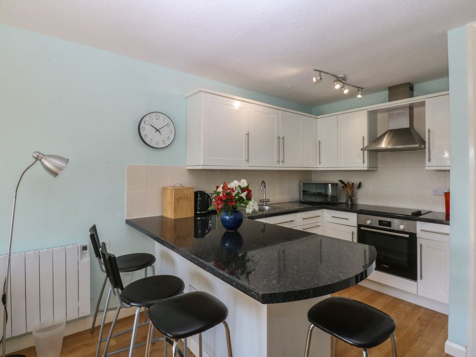 A kitchen with bar stools and appliances at 1 Oakley Wharf in Porthmadog