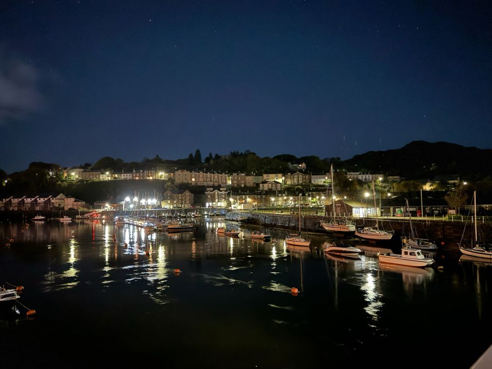 A harbor with boats and lights on the water at River's Edge Penthouse in Porthmadog