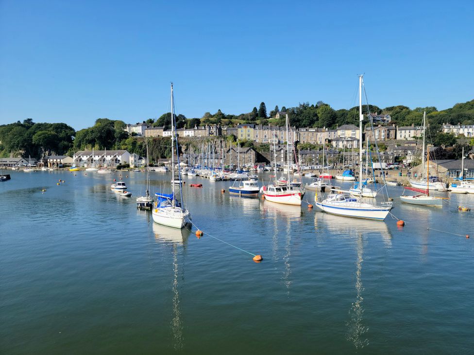 A view of boats in the harbor with houses on the hillside at River's Edge Penthouse in Porthmadog