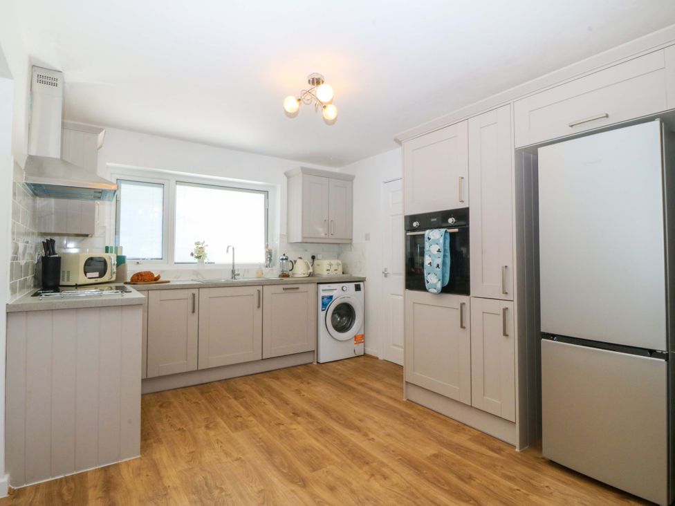 A kitchen with appliances and cabinets at 20 Gwelfor Estate in Cemaes Bay