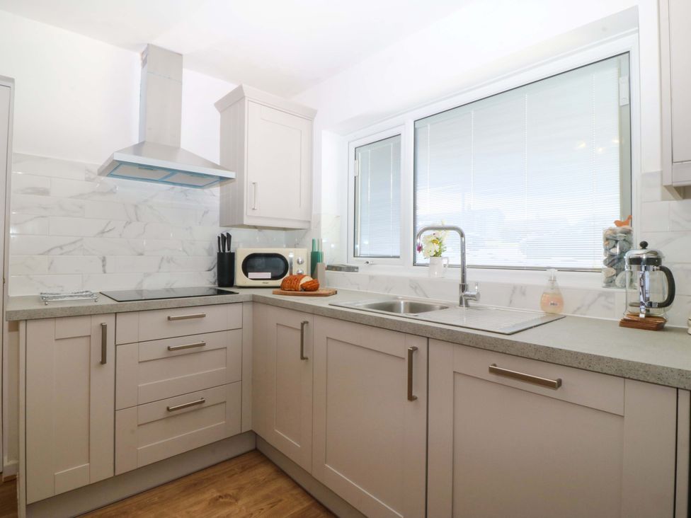 A kitchen with a sink and microwave at 20 Gwelfor Estate Cemaes Bay