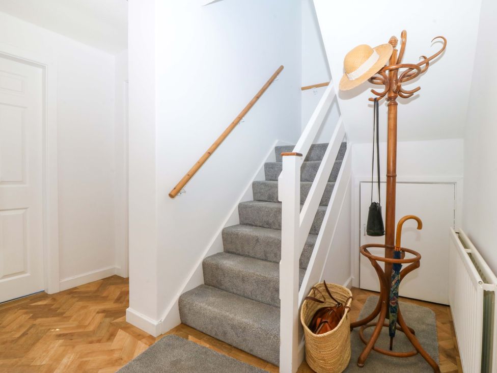 A hallway with a staircase and coat rack at 20 Gwelfor Estate Cemaes Bay