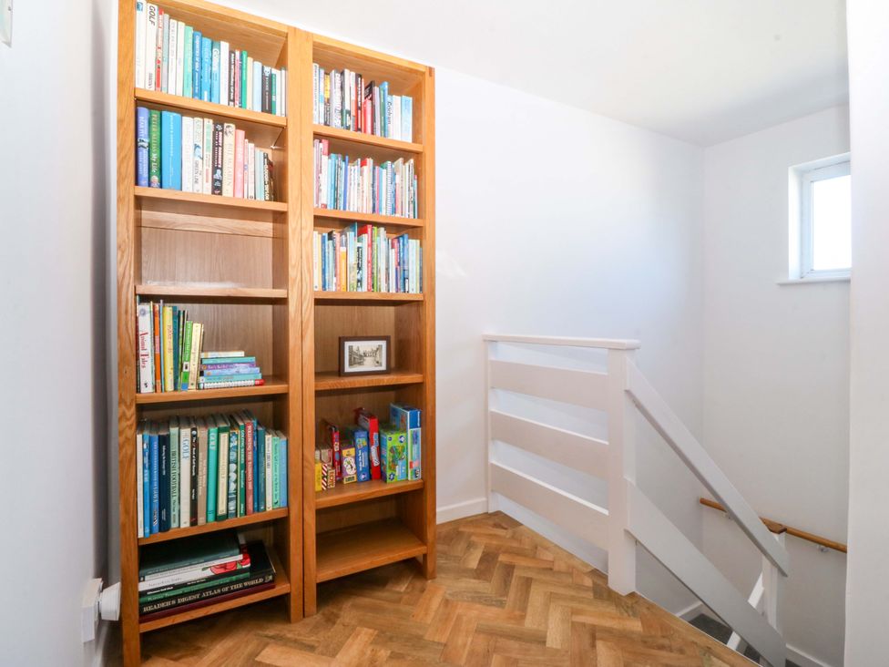 A hallway with a bookshelf and staircase at 20 Gwelfor Estate, Cemaes Bay