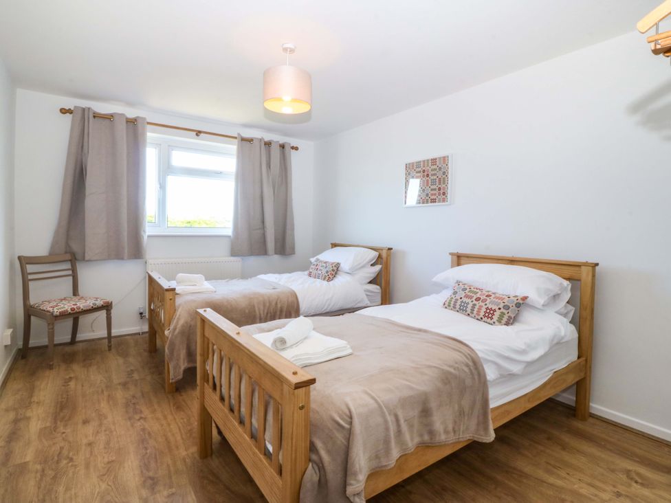 A bedroom with two beds and a chair at 20 Gwelfor Estate in Cemaes Bay