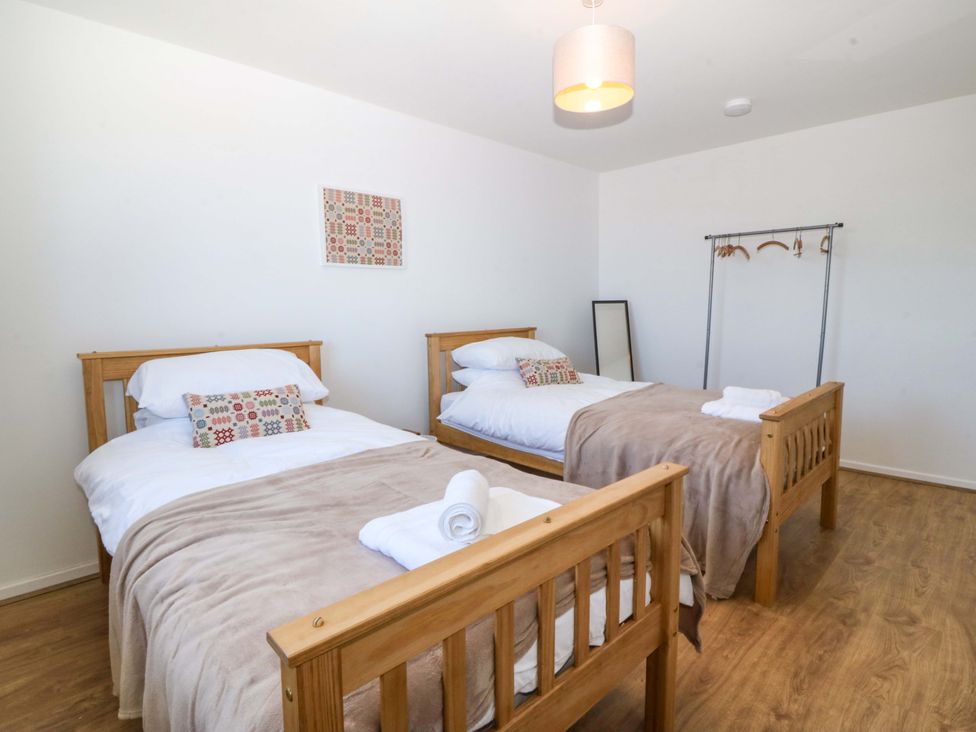 A bedroom with two beds and a clothes rack at 20 Gwelfor Estate Cemaes Bay
