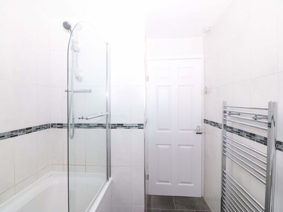A bathroom with bathtub, shower, towel radiator at 20 Gwelfor Estate Cemaes Bay