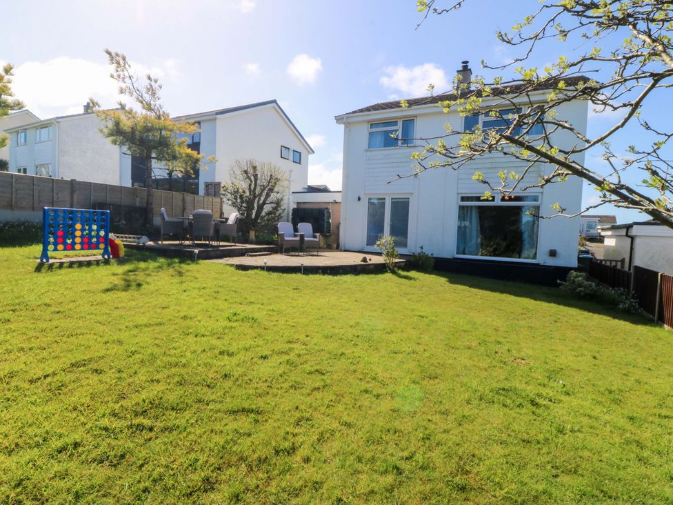 A garden with grass and patio chairs at 20 Gwelfor Estate in Cemaes Bay