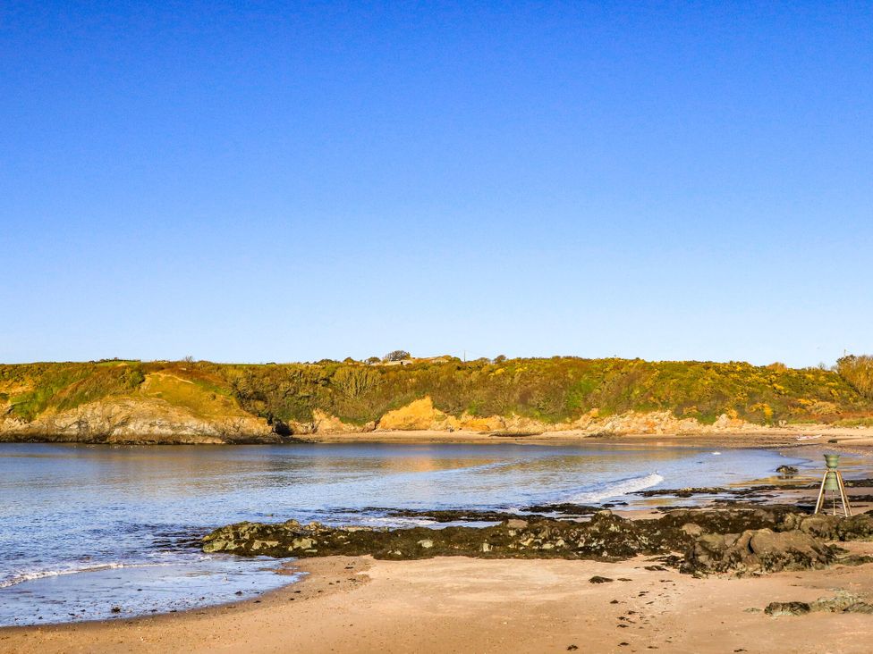 A beach with a rocky shore and hills at 20 Gwelfor Estate in Cemaes Bay