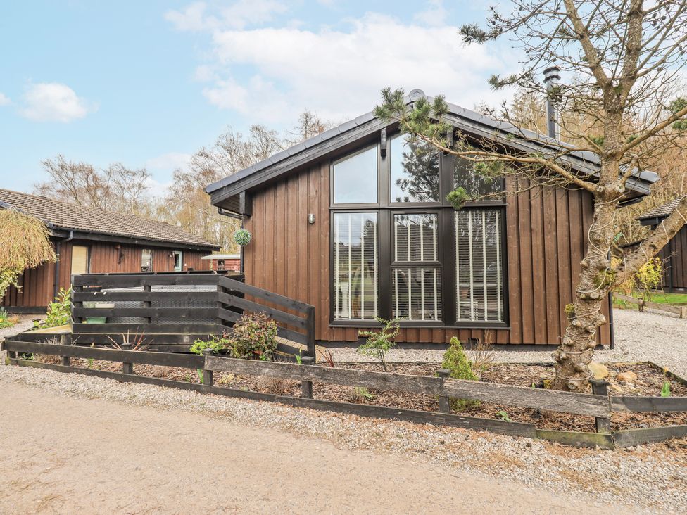 A wooden cabin with large windows and a path at Fig Tree Lodge in Hutton Roof near Penrith