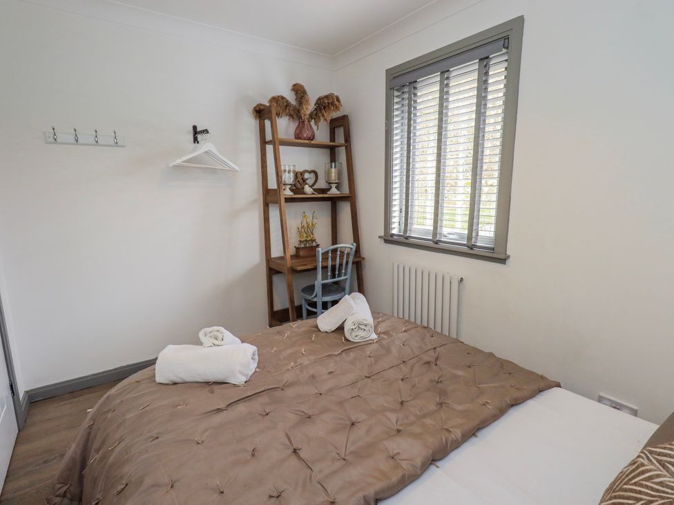 A bedroom with a bed and shelf at Fig Tree Lodge in Hutton Roof near Penrith