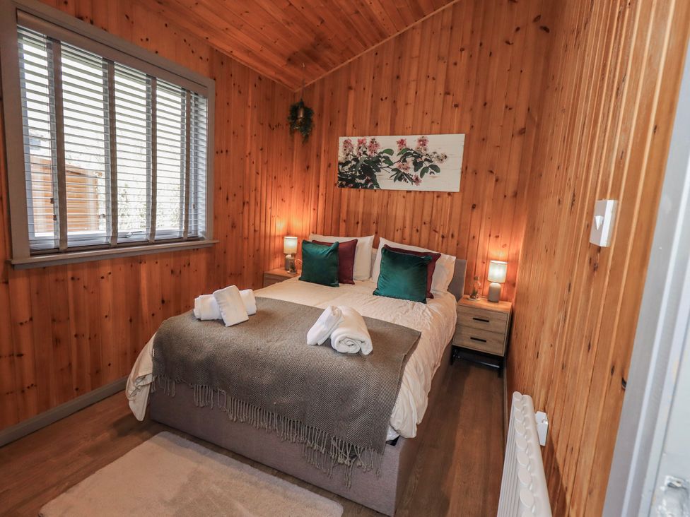 A bedroom with a double bed and wooden panels at Fig Tree Lodge in Hutton Roof near Penrith