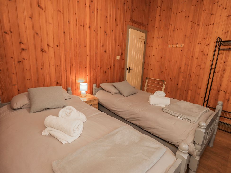 A bedroom with two beds and a bedside lamp at Fig Tree Lodge Hutton Roof near Penrith