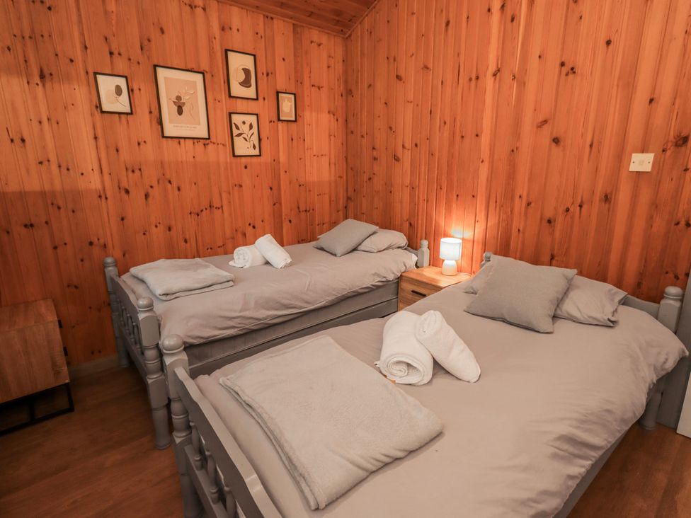 A bedroom with two beds and a nightstand at Fig Tree Lodge in Hutton Roof near Penrith