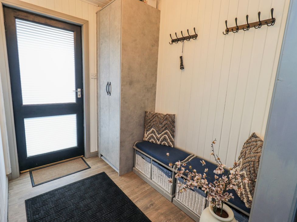 A hallway with a bench and coat hooks at Fig Tree Lodge Hutton Roof near Penrith