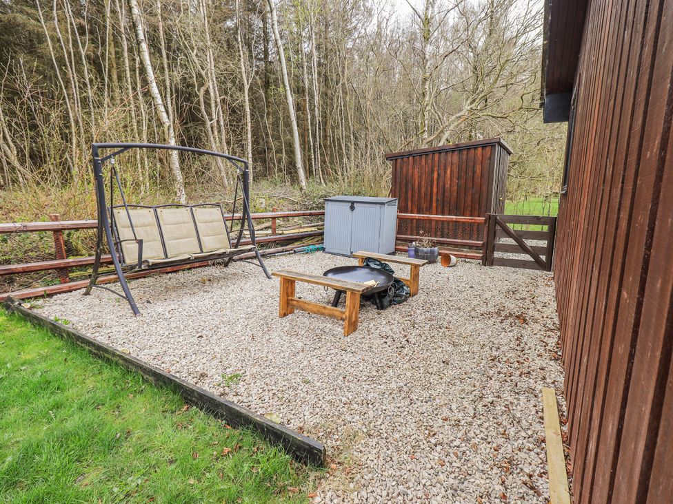 A garden with a swing seat and storage box at Fig Tree Lodge Hutton Roof near Penrith