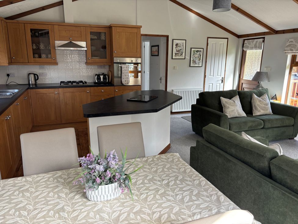 A kitchen and living room area with dining table and sofa at 2 Riverside Lodge Abercych near Cenarth