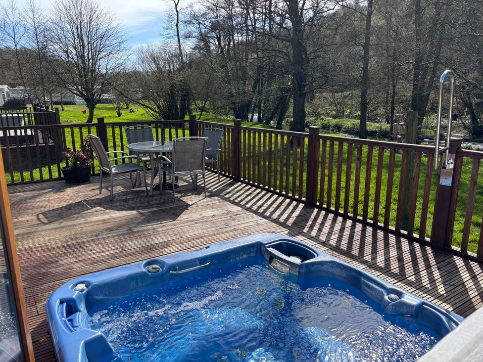 An outdoor area with a hot tub and seating at 2 Riverside Lodge Abercych near Cenarth