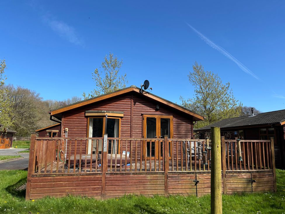 A cabin with a wooden deck and a satellite dish at 2 Riverside Lodge Abercych near Cenarth