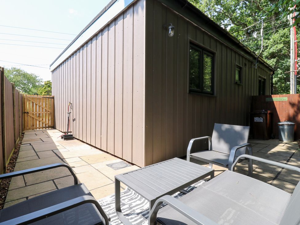 An outdoor area with chairs and a table beside a shed at Hub House Three Oaks near Hastings