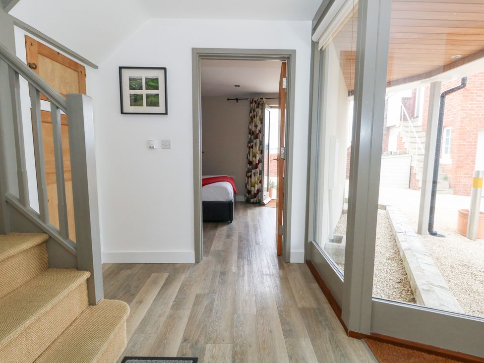 A hallway with stairs and a doorway leading to a bedroom at Coastguard Lookout in Wyke Regis