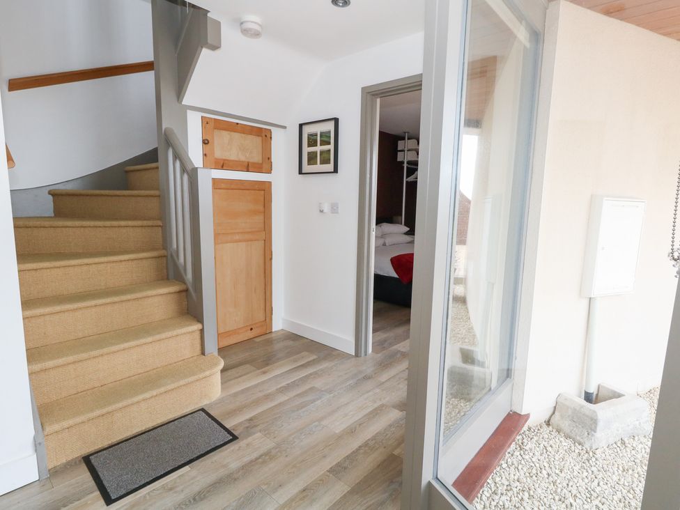 A hallway with a staircase and door to a bedroom at Coastguard Lookout in Wyke Regis