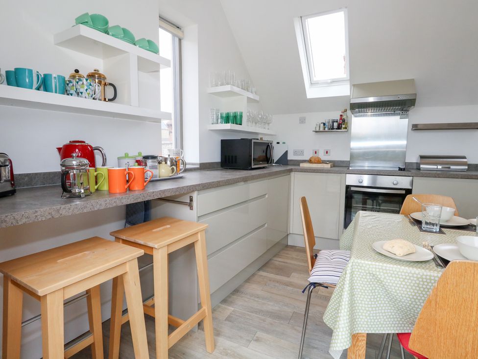 A kitchen with a counter, stools, and appliances at Coastguard Lookout in Wyke Regis