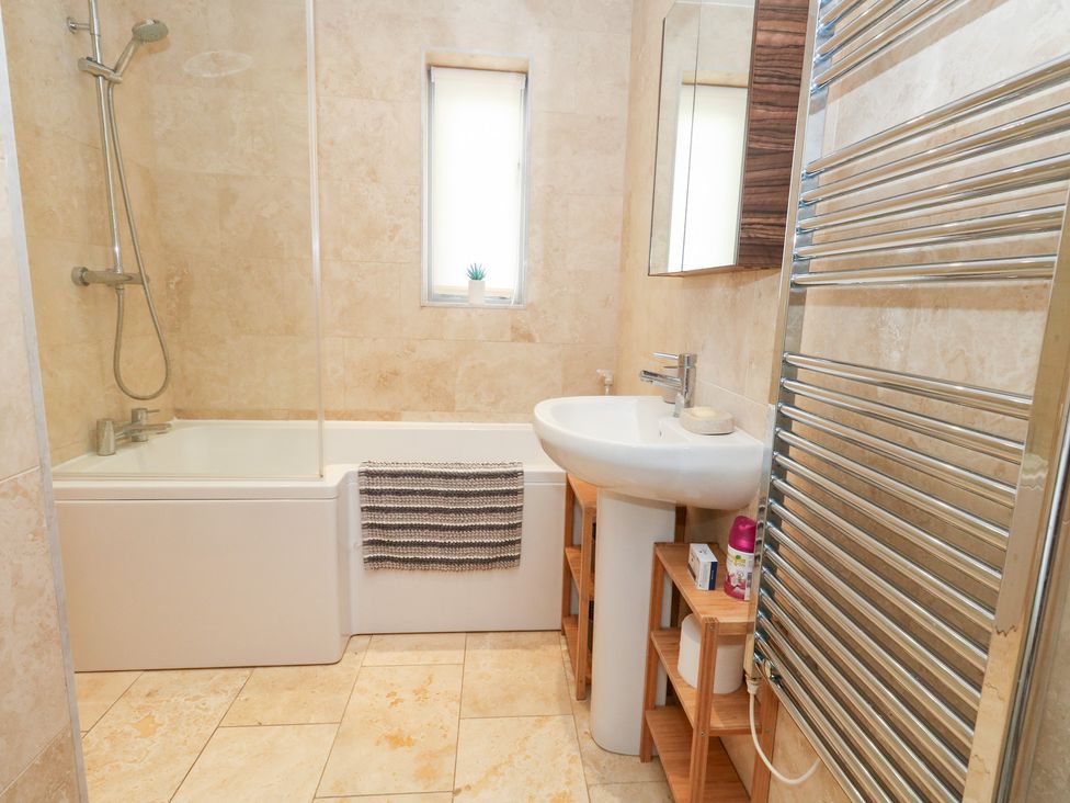 A bathroom with a bathtub, sink, and towel rack at Coastguard Lookout in Wyke Regis