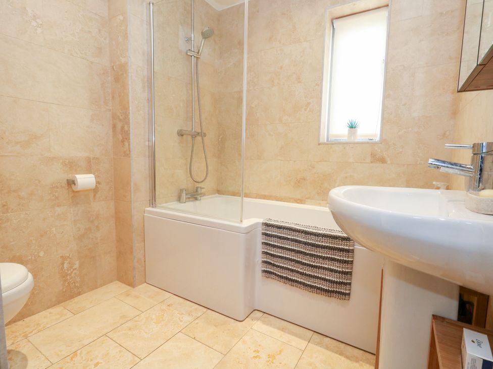 A bathroom with a bathtub, shower, toilet and sink at Coastguard Lookout in Wyke Regis