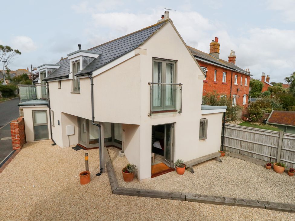 A house with a balcony and gravel area at Coastguard Lookout in Wyke Regis