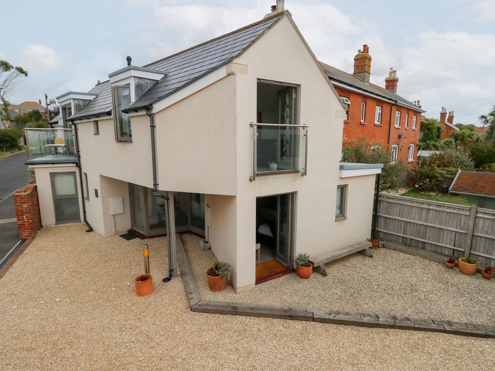 A house with a balcony and gravel area at Coastguard Lookout in Wyke Regis
