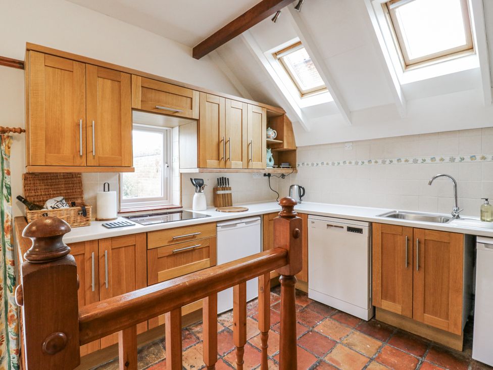A kitchen with wooden cabinets and a sink at White Gates in Banham