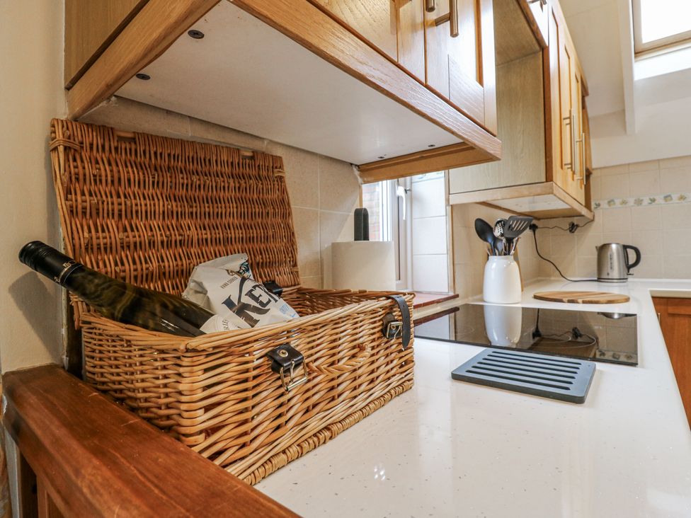 A kitchen with a basket, bottle, and utensils at White Gates in Banham