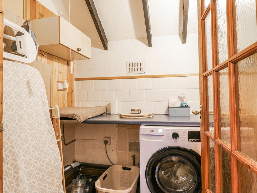 A laundry room with washing machine and ironing board at White Gates in Banham