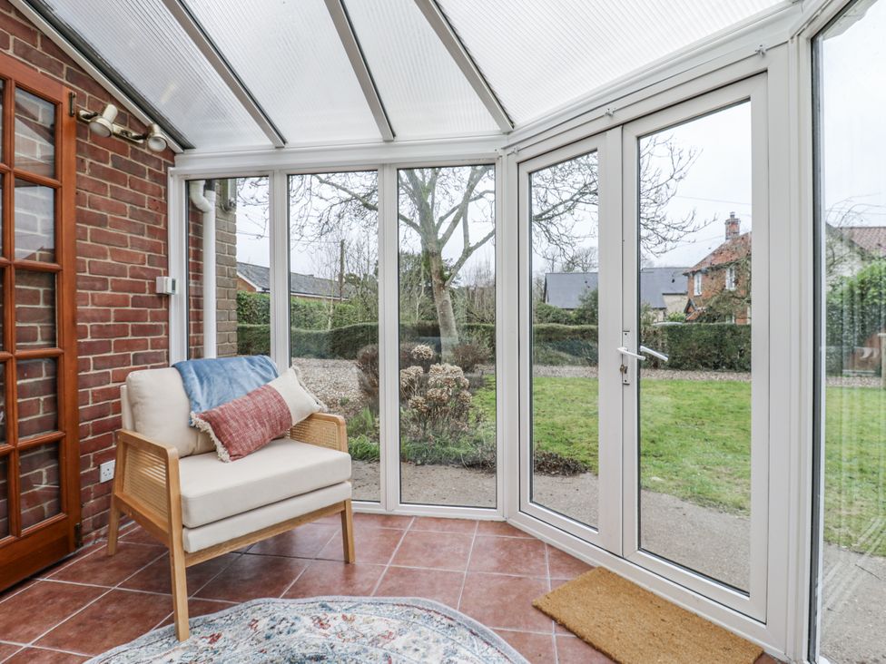 A conservatory with a chair and view of the garden at White Gates in Banham