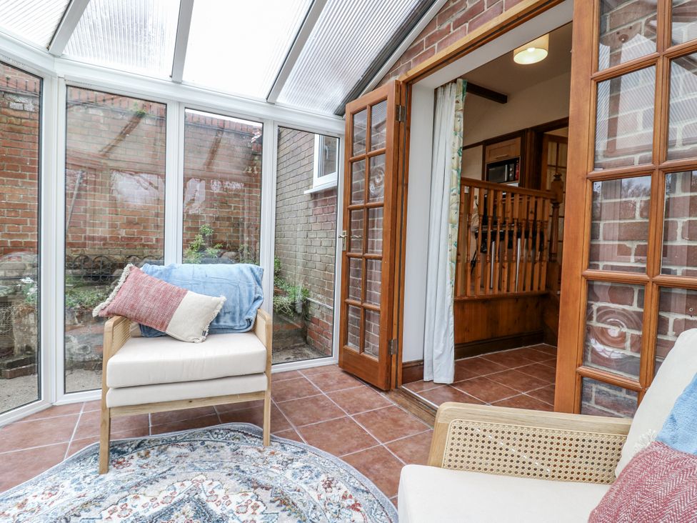 A conservatory with an armchair and rug at White Gates in Banham