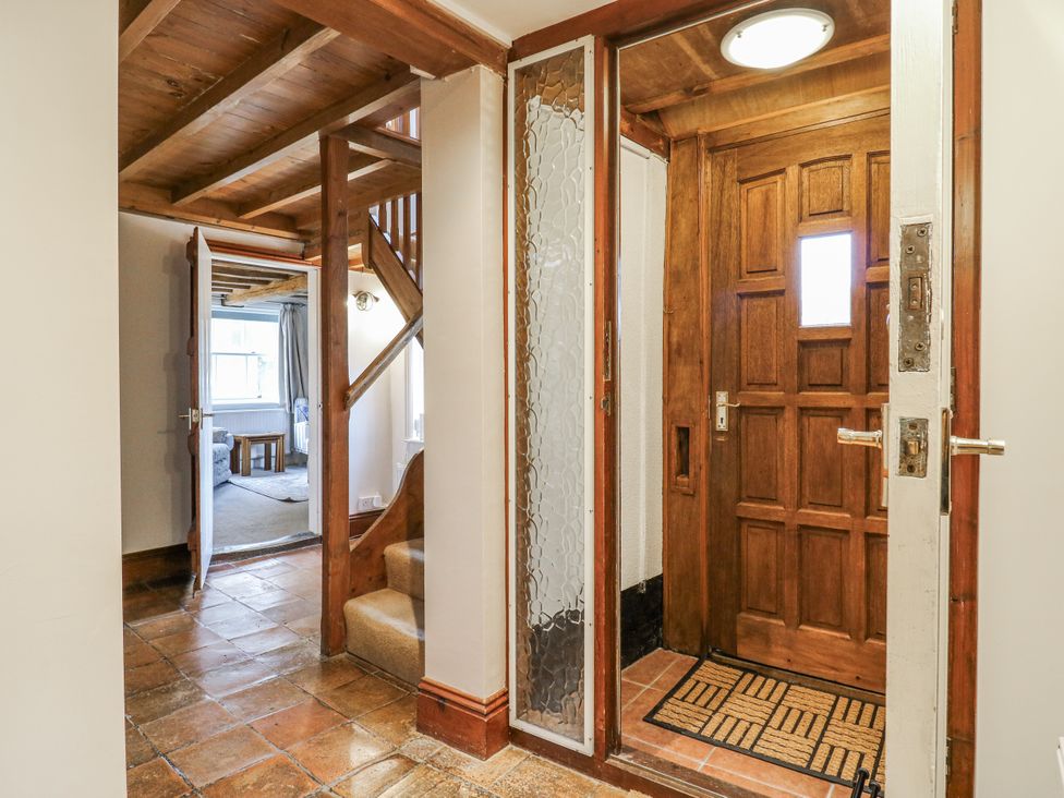 A hallway with a staircase and a door at White Gates in Banham