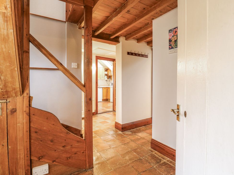 A hallway with a staircase and a door leading to the kitchen at White Gates in Banham